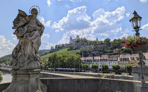 Statue auf einer Brücke mit Festung Marienberg im Hintergrund in Würzburg.