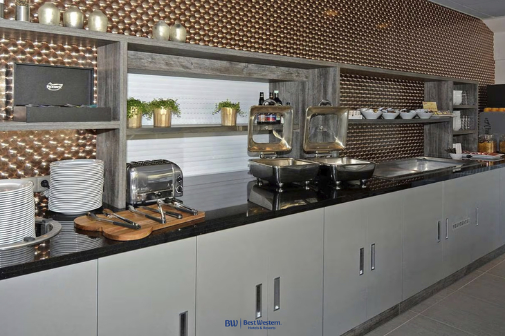 Buffetbereich mit Tellern, Toaster, Speisen und Pflanzen in modernem Best Western Hotel.