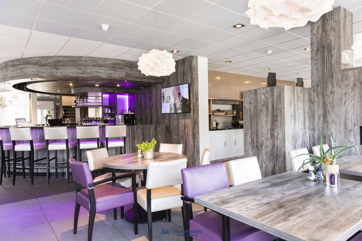 Innenansicht einer modernen Hotelbar mit stilvoller Einrichtung und lila Akzenten.