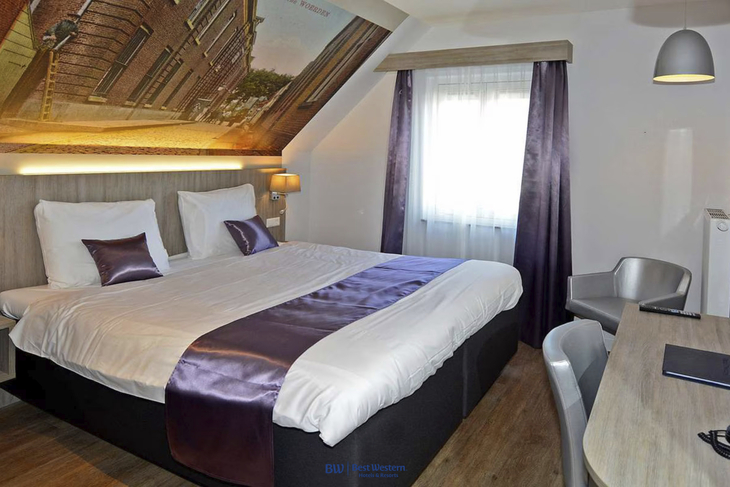Hotelzimmer mit Doppelbett, Schreibtisch und Fenster, moderne Einrichtung.