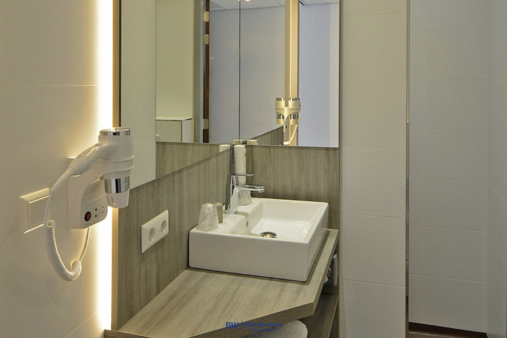 Modernes Hotelbadezimmer mit Waschbecken, Spiegel und Haartrockner.