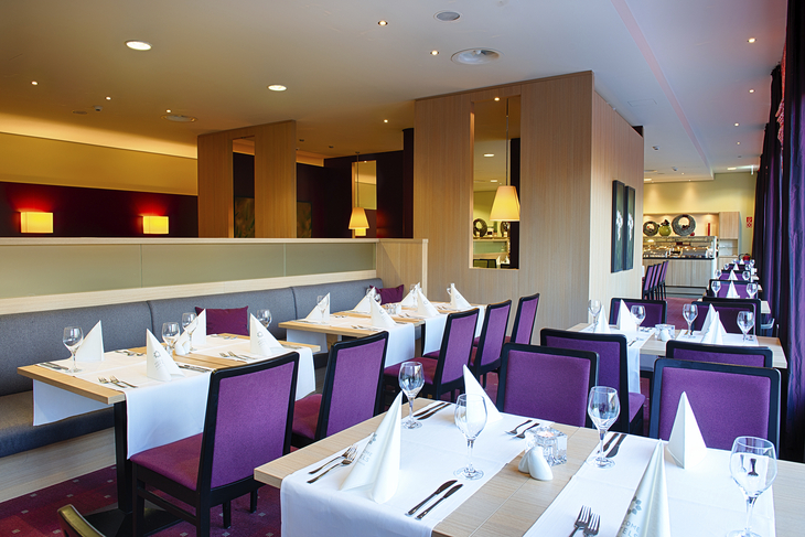 Elegantes Restaurant mit gedeckten Tischen und lila Stühlen im Welcome Hotel Paderborn.