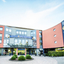 Eingang des Welcome Hotels in Paderborn mit auffälliger Fassade und Schildern.