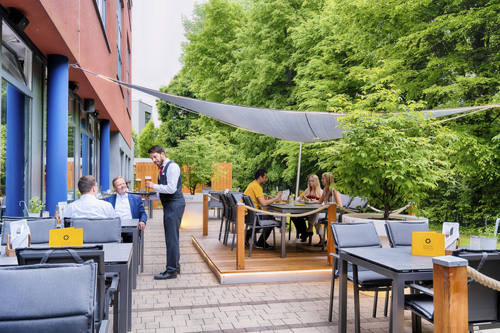 Terrasse des Welcome Hotels Paderborn mit Gästen und grüner Umgebung