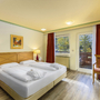 Doppelzimmer mit Doppelbett, zwei Stühlen, Fenster und Wandbild.