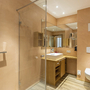Modernes Badezimmer mit Dusche, Waschbecken und Toilette in Holzoptik.