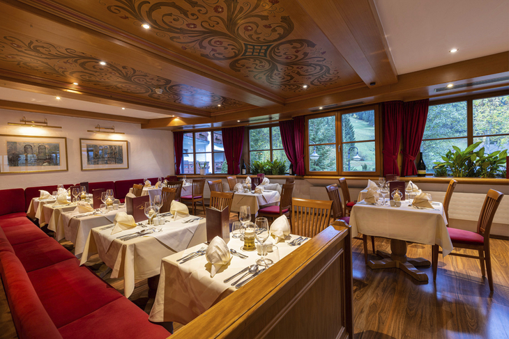 Gemütliches Restaurant mit gedeckten Tischen und dekorativer Holzdecke.