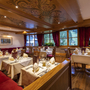Gemütliches Restaurant mit gedeckten Tischen und dekorativer Holzdecke.