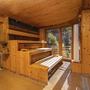 Holzsauna mit Fenstern und Blick auf bewaldete Berge.