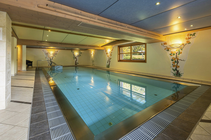 Innenpool mit dekorativen Wänden und seitlichem Fenster im Wellnessbereich.