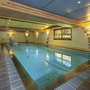 Innenpool mit dekorativen Wänden und seitlichem Fenster im Wellnessbereich.