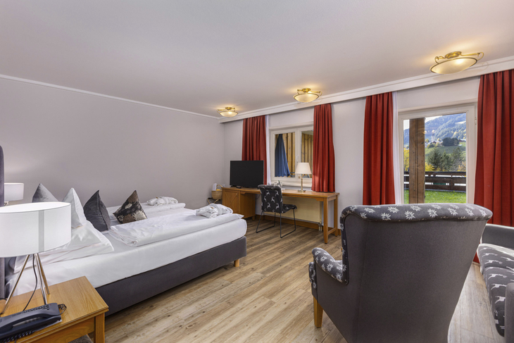 Komfortables Doppelzimmer mit Bett, Schreibtisch und Balkonblick.