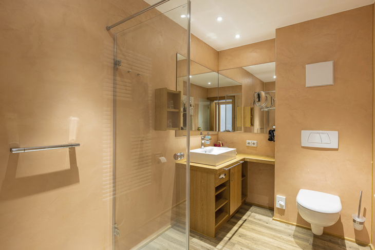 Modernes Badezimmer mit Dusche, Waschbecken und Toilette in Holzoptik.