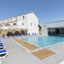 Außenpool mit Liegestühlen vor weißem Gebäude bei Sonnenschein