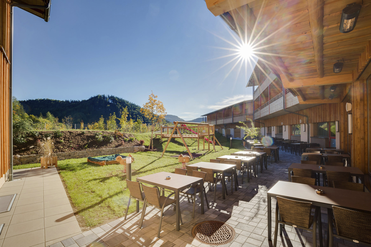Sonnenterrasse und Spielplatz im JUFA Hotel Annaberg, umgeben von Bergen.
