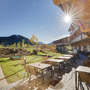 Sonnenterrasse und Spielplatz im JUFA Hotel Annaberg, umgeben von Bergen.