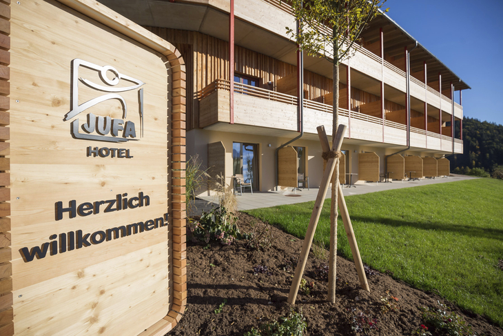 Außenansicht des JUFA Hotel Annaberg mit Balkon und Willkommensschild im Sommer.