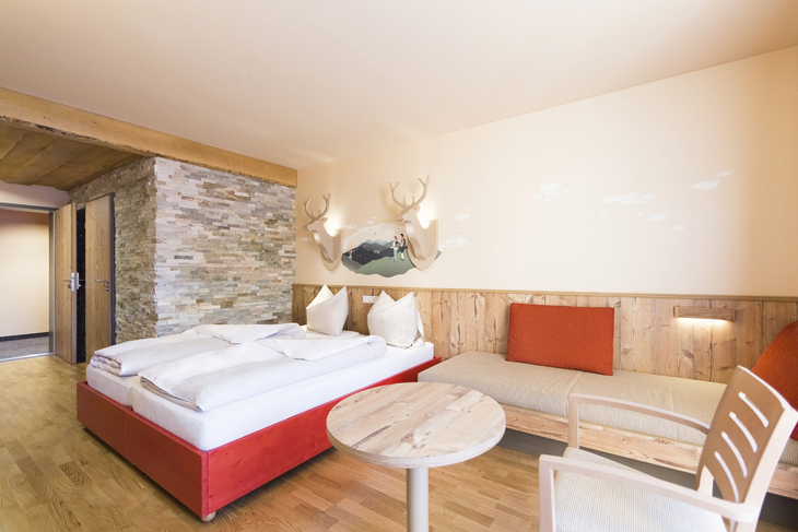 Doppelzimmer mit Doppelbett und Sitzgelegenheit im JUFA Hotel Annaberg.
